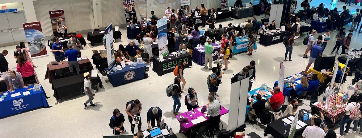 An arial view of a UC career fair. Students browsing tables set up my potential employers. 